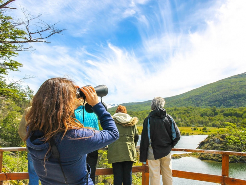 Uma pessoa olha através de um par de binóculos para a paisagem da excursão.