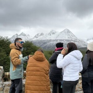 Guia de Kaitek con un grupo en un mirador frente a los montes nevados de Ushuaia