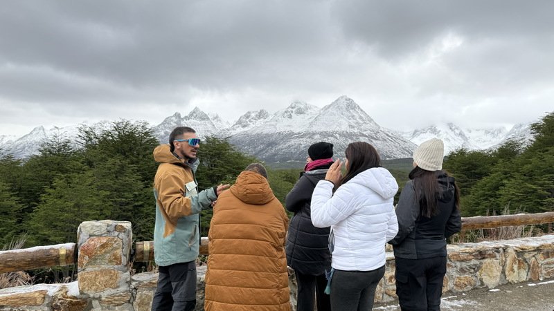 Guia de Kaitek con un grupo en un mirador frente a los montes nevados de Ushuaia