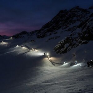 Fila de caminantes con linternas subiendo al Glaciar Martial de noche