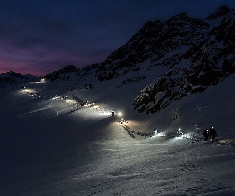 Fila de caminantes con linternas subiendo al Glaciar Martial de noche