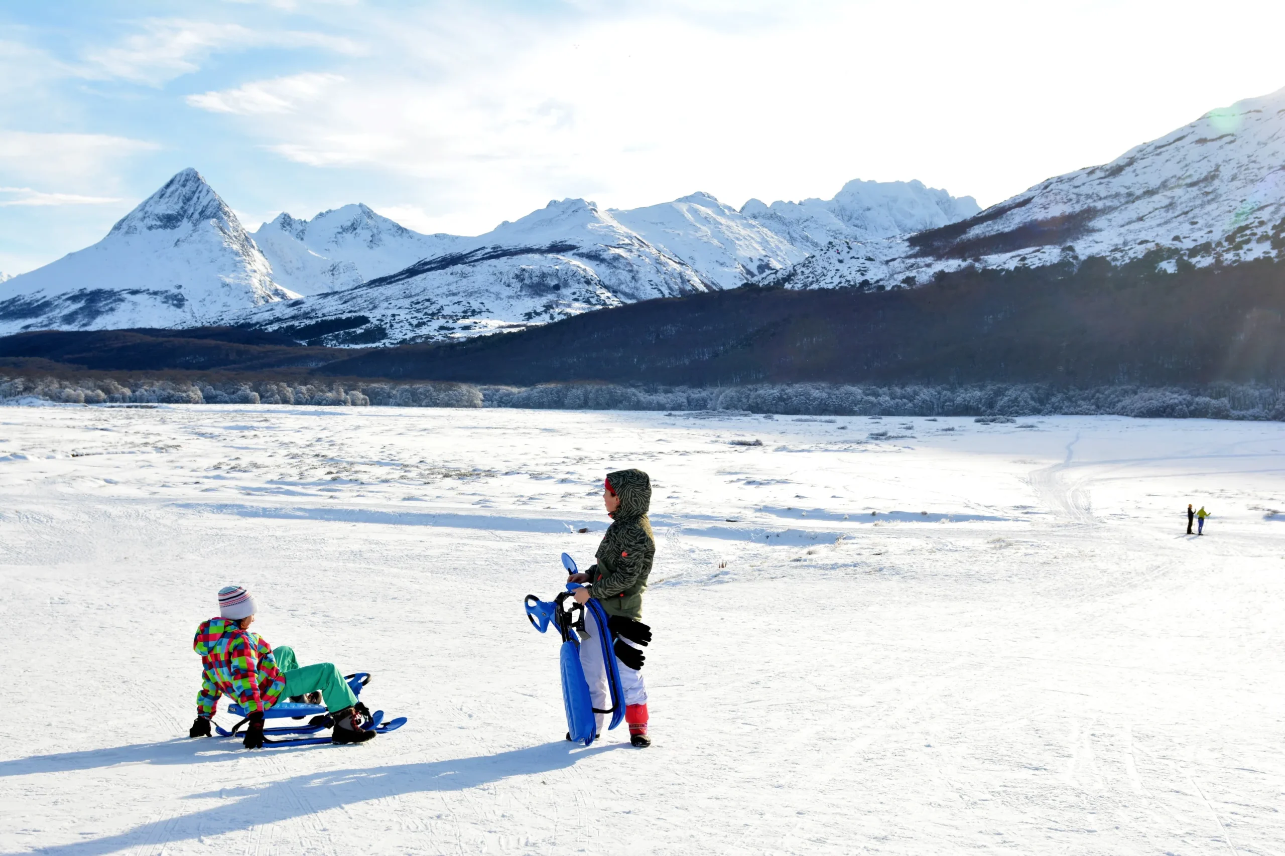 Niños con trineo frente a la cordillera nevada
